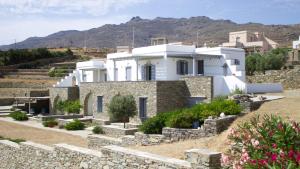 a white house with a stone wall at Rosalie Home - Aegean Poseidon in Tinos