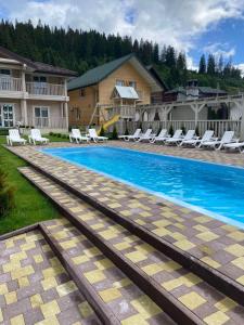 ein großer Swimmingpool mit Stühlen und ein Haus in der Unterkunft Pogar White in Slawske