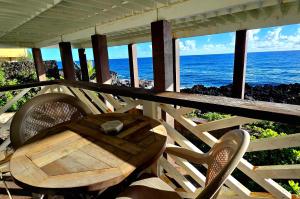 a wooden table and chair on a balcony with the ocean at Oceanfront studio see whales and dolphins in Pahoa
