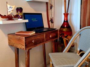 a laptop computer sitting on a wooden desk next to a chair at Oceanfront studio see whales and dolphins in Pahoa +13 photos