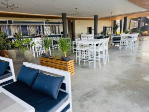 a restaurant with white tables and white chairs and plants at Endless Summer Seafront - 1BR Beach Resort Condo in San Juan