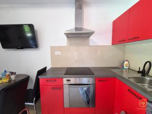 a kitchen with red cabinets and a sink and a stove at Riverside Apartments - pet friendly in Sečovlje