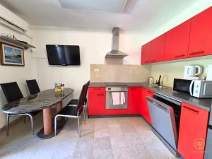 a kitchen with red cabinets and a table with chairs at Riverside Apartments - pet friendly in Sečovlje