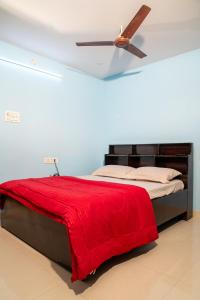 a bed with a red blanket and a ceiling fan at My3 Dwarkamai in Vijayawāda