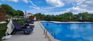 a large swimming pool with chairs next to a building at Infinity Studio, Shkorpilovtsi in Shkorpilovtsi