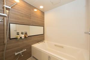 a bathroom with a tub and a shower with a mirror at Hillside Sea View Resort Villa Gushikumui in Motobu +21 photos