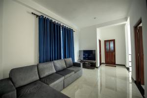 a living room with a couch and blue curtains at Green Infinity Resorts in Diyatalawa