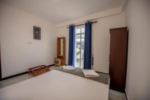 a room with a bed and a window with blue curtains at Green Infinity Resorts in Diyatalawa +27 photos