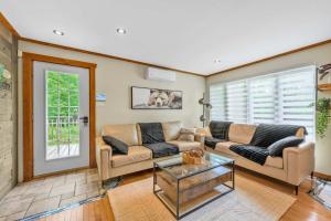 a living room with two couches and a glass table at Spa Game room Waterfront - Le Refuge Vert in Brébeuf