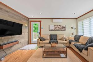 a living room with a couch and a tv at Spa Game room Waterfront - Le Refuge Vert in Brébeuf