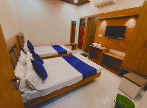 a bedroom with two beds with blue pillows and a television at Hotel Shree krishna in Ujjain