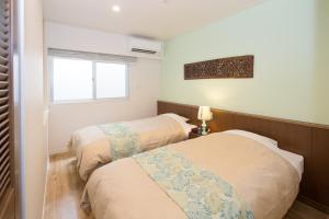 two beds in a small room with a window at Hillside Sea View Resort Villa Gushikumui in Motobu