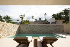 a swimming pool with two chairs and a stone wall at KW3 Villas in Mae Nam