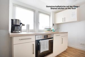 a kitchen with white cabinets and a stove top oven at Schöne Apartments I Kostenloses Parken I home2share in Münster