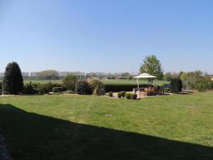 a large grass field with a table and an umbrella at Maikes home in Torhout