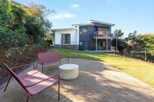 a house with two chairs and a table in front of it at Perfectly Pambula in Pambula Beach