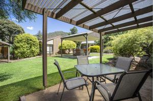 a patio with a table and chairs under a pergola at The Bright Resort in Bright