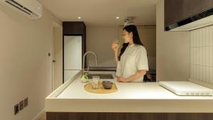 a woman standing in a kitchen drinking from a glass at Anook Stay Daejeon Daeheung in Daejeon +98 photos