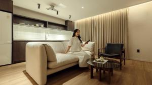 a woman sitting on a couch in a living room at Anook Stay Daejeon Daeheung in Daejeon