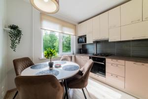 a kitchen with a white table and chairs at VakarDi Apartments in Šiauliai