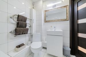 a white bathroom with a toilet and a mirror at VakarDi Apartments in Šiauliai +18 photos