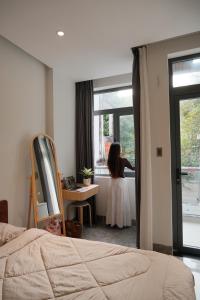 a woman standing in a bedroom looking out the window at Thỏ Chill Homestay in Vung Tau