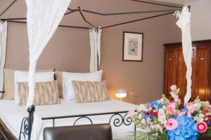 een slaapkamer met een hemelbed versierd met bloemen bij Hotel De Hofkamers in Oostende +45 foto's