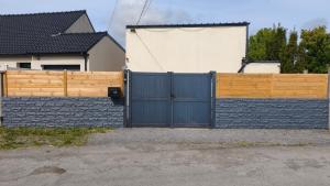 a fence with a blue gate in front of a house at Maison chaleureuse avec parking gratuit sur place in Coulogne +1 photo