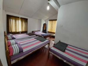a room with three beds in it with windows at Sanara Hotel in Nuwara Eliya