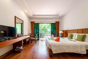 a bedroom with a bed and a desk and a television at Sailom Resort Bangsaphan in Bang Saphan