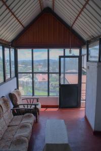 a living room with a couch and tables and windows at Sanara Hotel in Nuwara Eliya