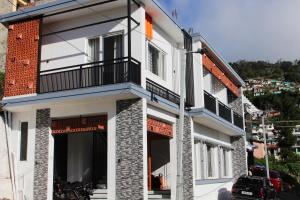 a white building with a balcony on a street at Altiora Homestay in Kodaikānāl
