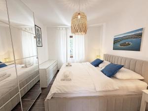 a white bedroom with a large bed and a chandelier at Family Apartments Monika - sea view - heated pool II in Punat +64 photos