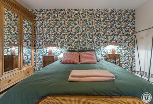 a bedroom with a large bed with a green blanket at Le logis du lièvre in Lodes
