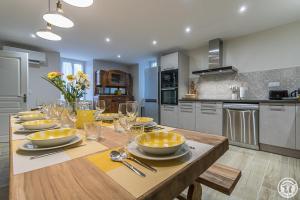 a kitchen with a wooden table with plates and wine glasses at Le logis du lièvre in Lodes