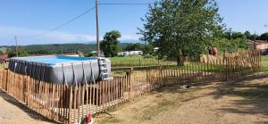 a fence with a pool in it next to a field at Le logis du lièvre in Lodes