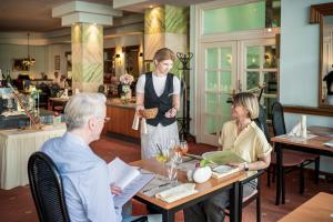 a woman standing at a table in a restaurant at Parkhotel Klüschenberg in Plau am See