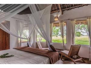 a bedroom with a bed and two chairs and windows at Mikumi Wilderness Camp in Kikoboga