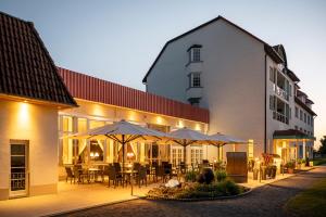 a building with tables and umbrellas in front of it at Parkhotel Klüschenberg in Plau am See