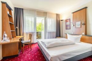 a bedroom with a bed and a desk and a window at Parkhotel Klüschenberg in Plau am See +59 photos