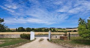 a road leading into a field with a stone wall at B&B Le Chardon in Saint-Gervais-les-Trois-Clochers