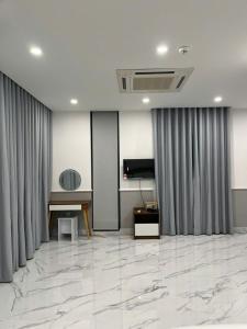 a living room with marble floors and gray curtains at Cozy Corner Beach Hotel in Phú Quốc