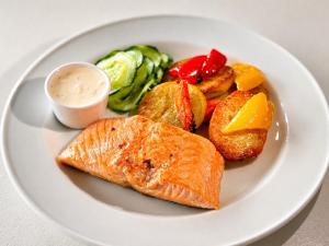 a white plate with fish and vegetables and a sauce at Hotel Carl XII in Ed