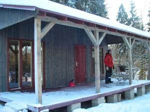 a man standing on the porch of a cabin in the snow at Kempings Ozolkalns in Cēsis