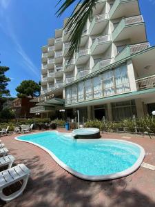 a swimming pool in front of a building at Hotel Monaco - parcheggio e piscina in Milano Marittima