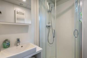 a white bathroom with a shower and a sink at Holiday Home Tiny Haus Sunside in Riedenburg +28 photos