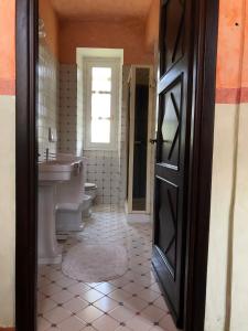 a bathroom with a sink and a toilet and a door at Cascina Bolichin in Diano dʼAlba