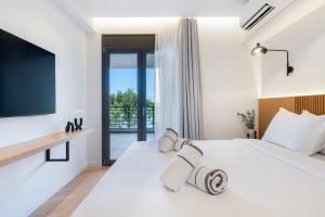 a bedroom with a large white bed and a balcony at Urban Heights Ammoudi Seafront in Agios Nikolaos