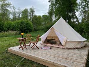 a tent with a table and chairs on a wooden deck at Ilmjärve Glamping Otepää in Ilmjärve