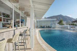 a swimming pool with chairs and a bar next to a house at Bella Santorini Hotel in Perivolos